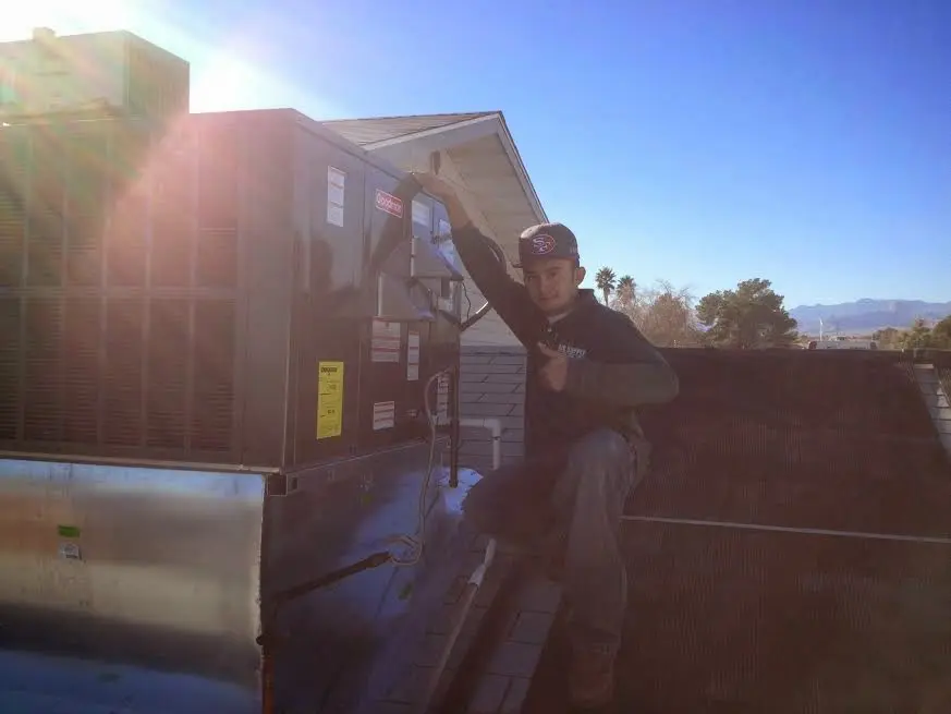HVAC technician performing Air Duct Cleaning on a rooftop unit in Paradise